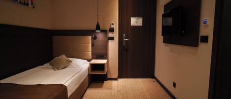 Habitación de hotel con cama, mesita de noche, lámpara y una puerta con un mapa.
