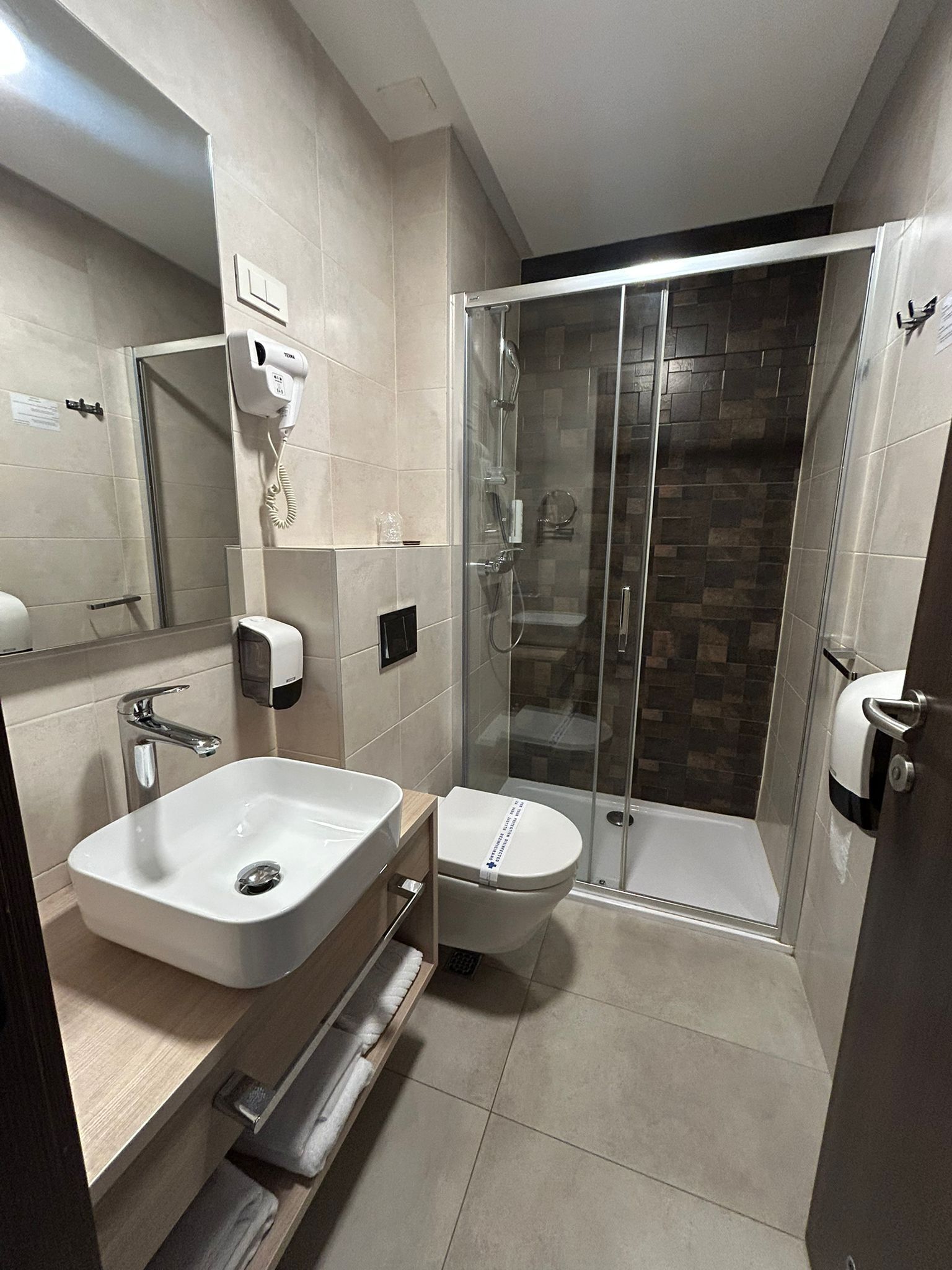 Un baño moderno con ducha de vidrio, lavamanos e inodoro.