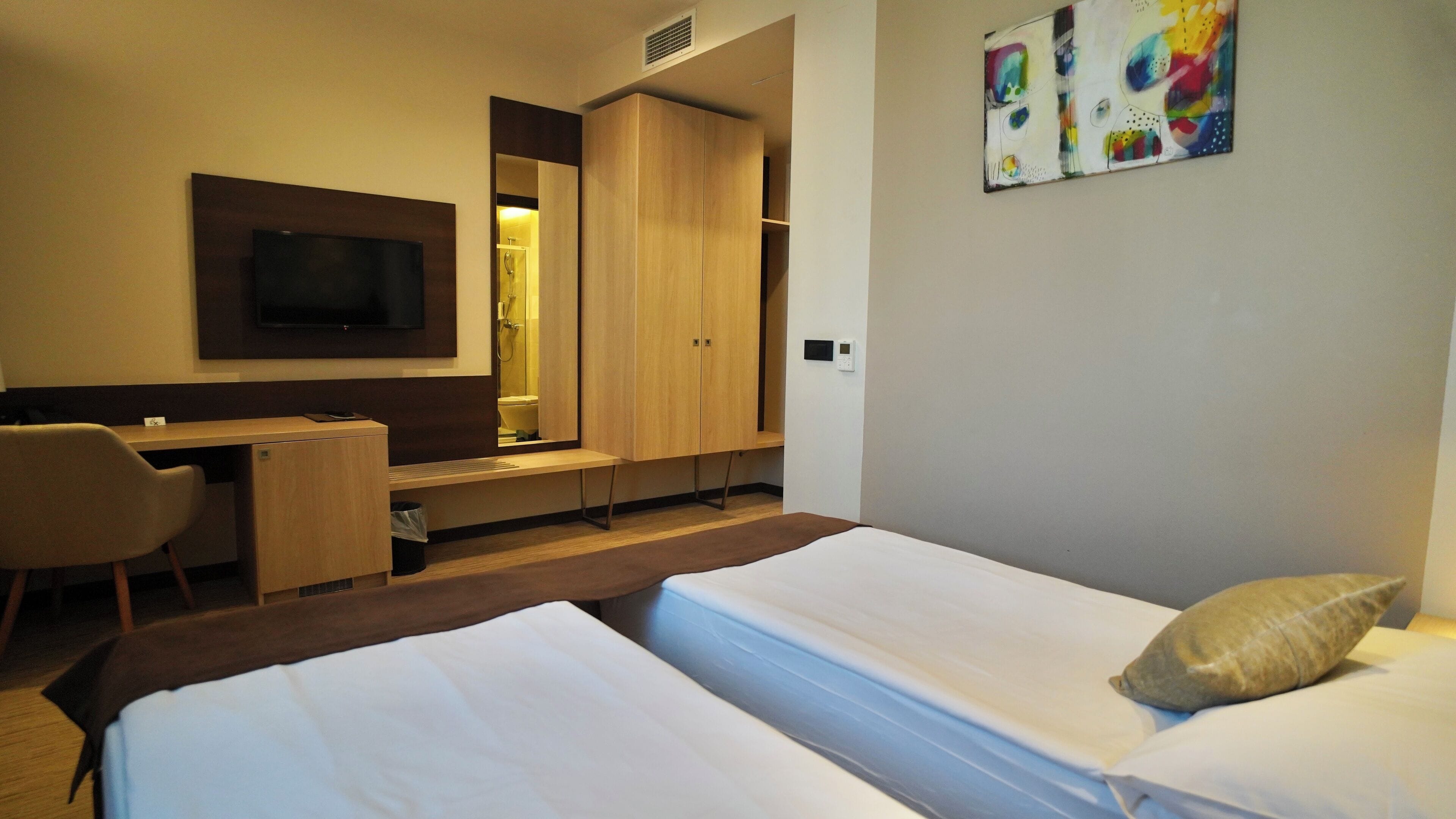 Une chambre d’hôtel équipée d’un lit, d’un bureau, d’une chaise, d’une télévision et d’une armoire.