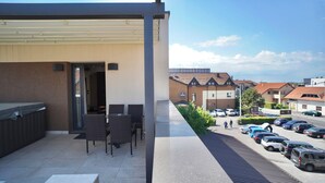 A terrace with outdoor seating and a view of a parking area and buildings in the background. - Hotel Gallus (Zagreb)