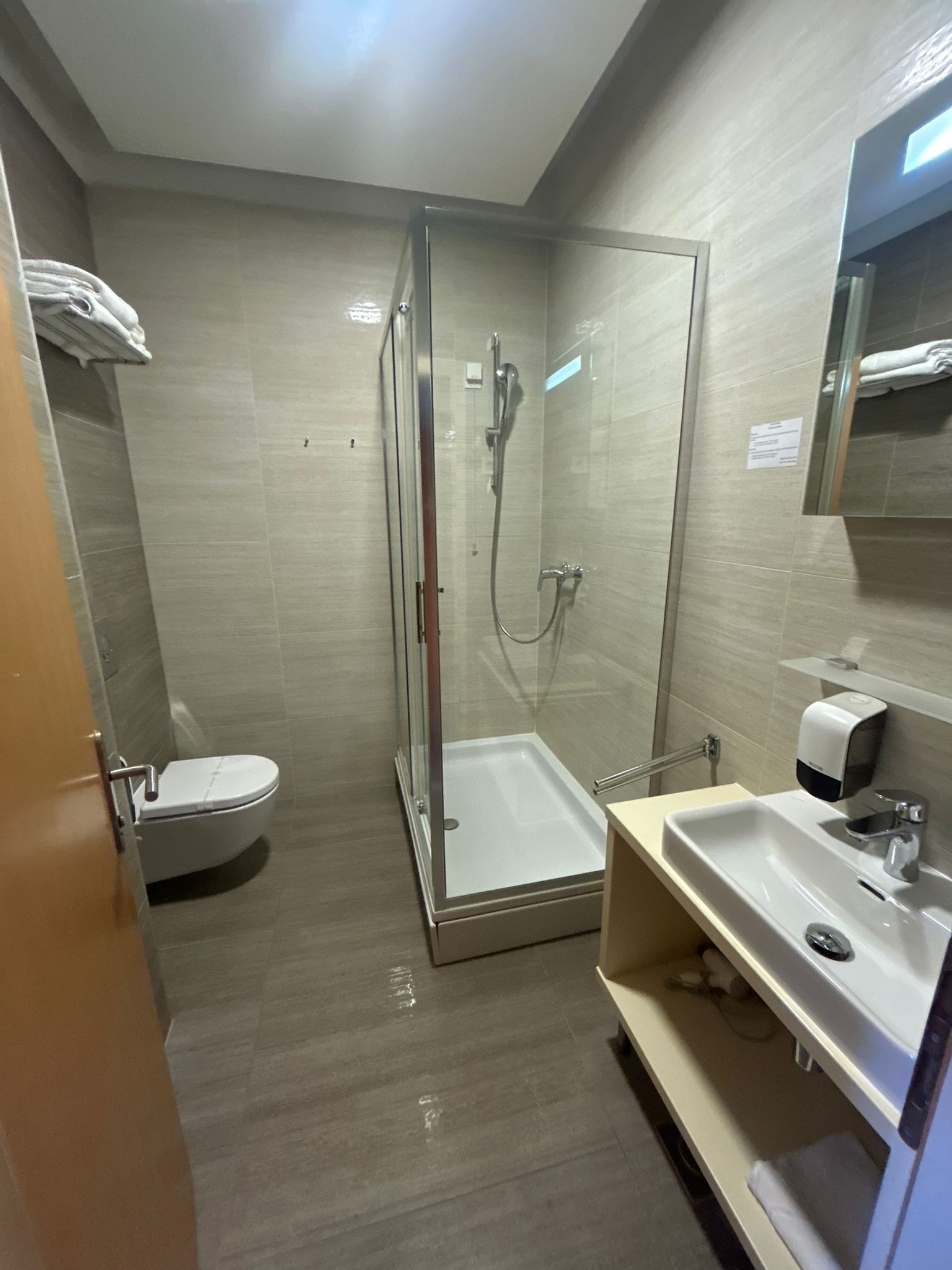 Une salle de bain moderne avec une douche à parois de verre, des toilettes et un lavabo équipé d’un distributeur de savon.
