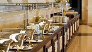 Ein Buffet mit durchsichtigen Glasabdeckungen über den Speisen, einer Holztresen und einem gefliesten Boden.