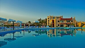 Ein Hotel mit Schwimmbad, Liegestühlen und Sonnenschirmen.