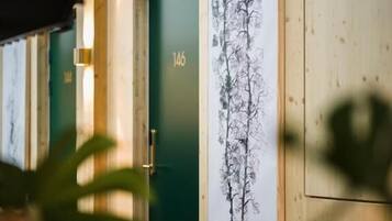A room with a green door labeled '146', a wall-mounted artwork, and a potted plant in the foreground.