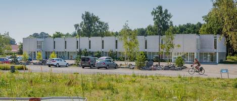 Een modern gebouw met een parkeerplaats en een fietser.