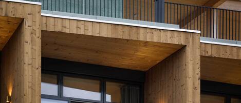 Un edificio de madera de varios pisos con balcones, ventanas amplias e iluminación exterior.
