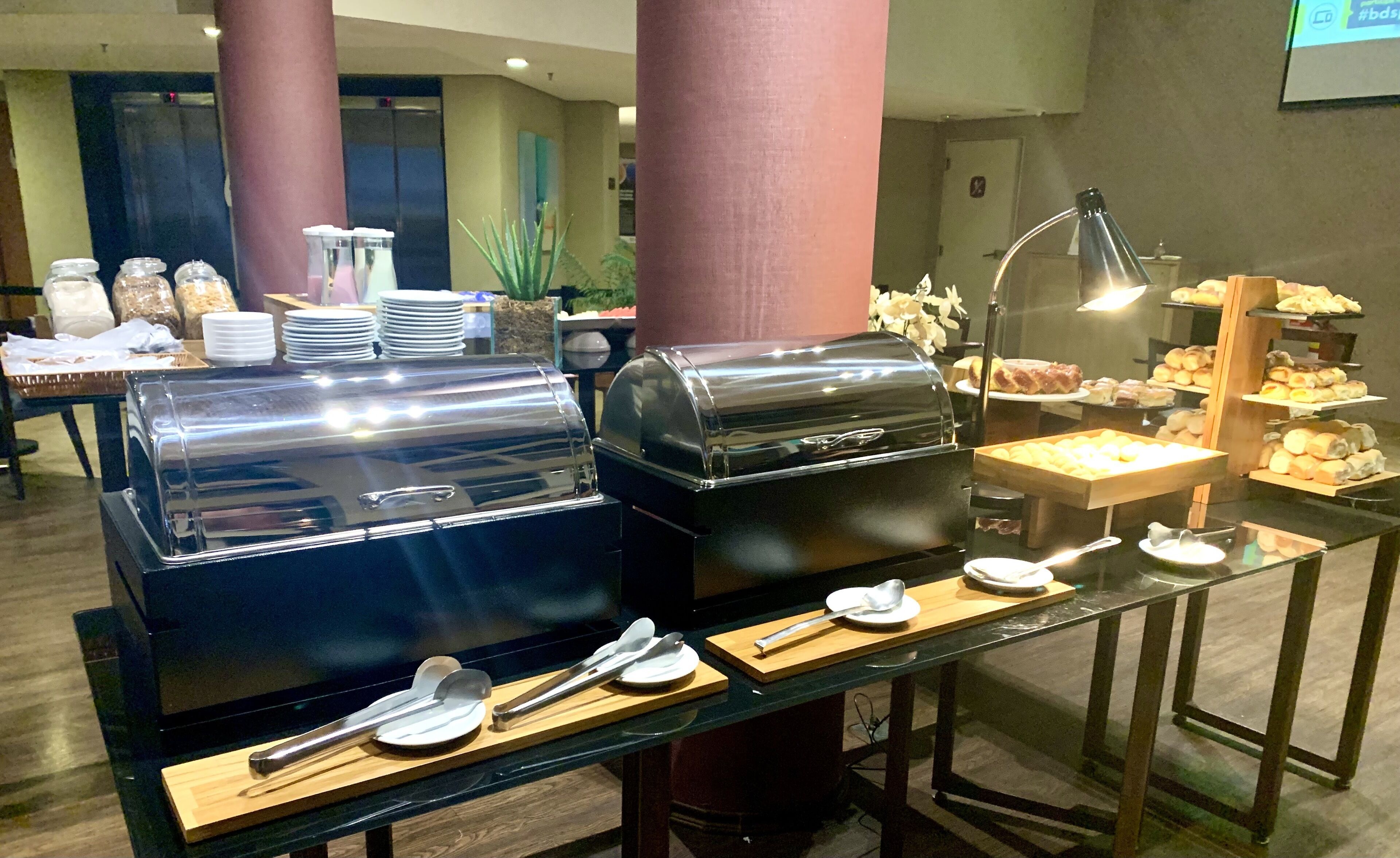A buffet setup with two large food warmers, serving utensils, and a variety of food items on display.