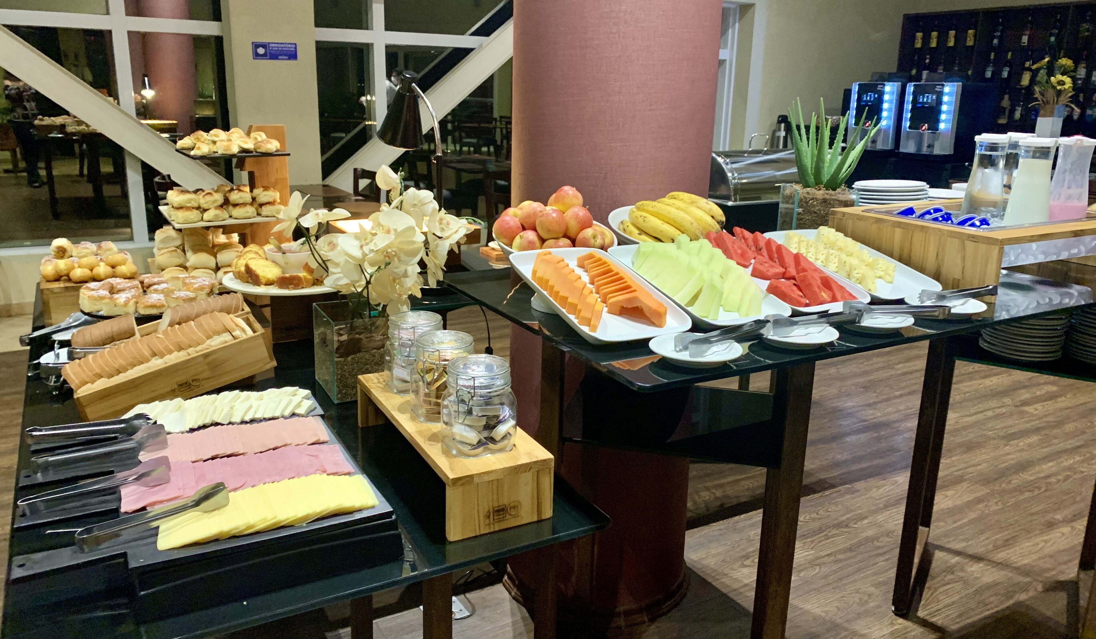 Un bufé con diversos alimentos, entre ellos frutas, pasteles y quesos.