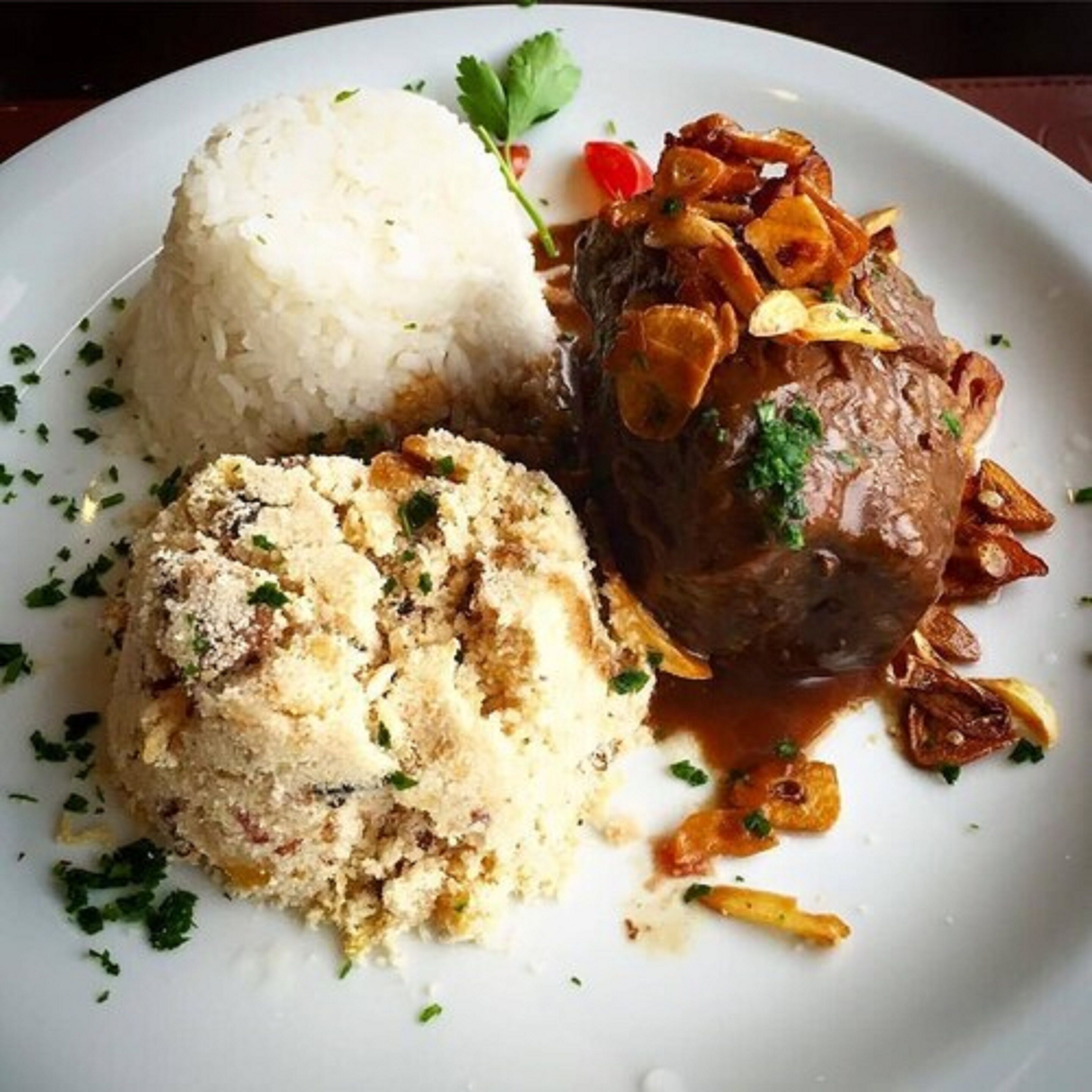 Un plato con carne, arroz y un acompañamiento tipo pan.