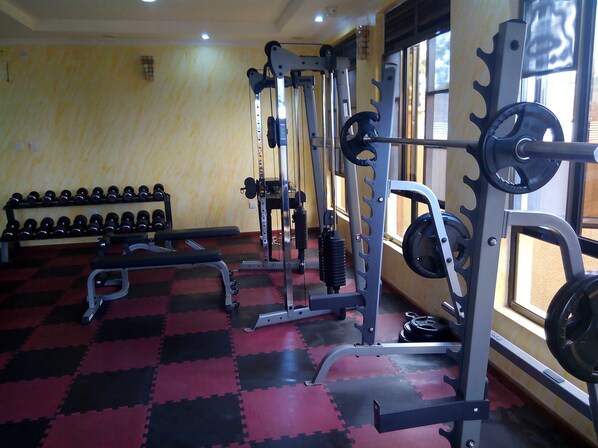 A gym with weightlifting equipment, benches, and dumbbells.