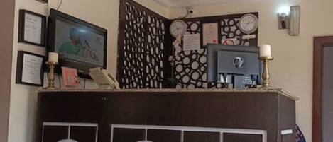 A reception area with a wooden counter, framed certificates, a clock, and a small desk with a telephone.
