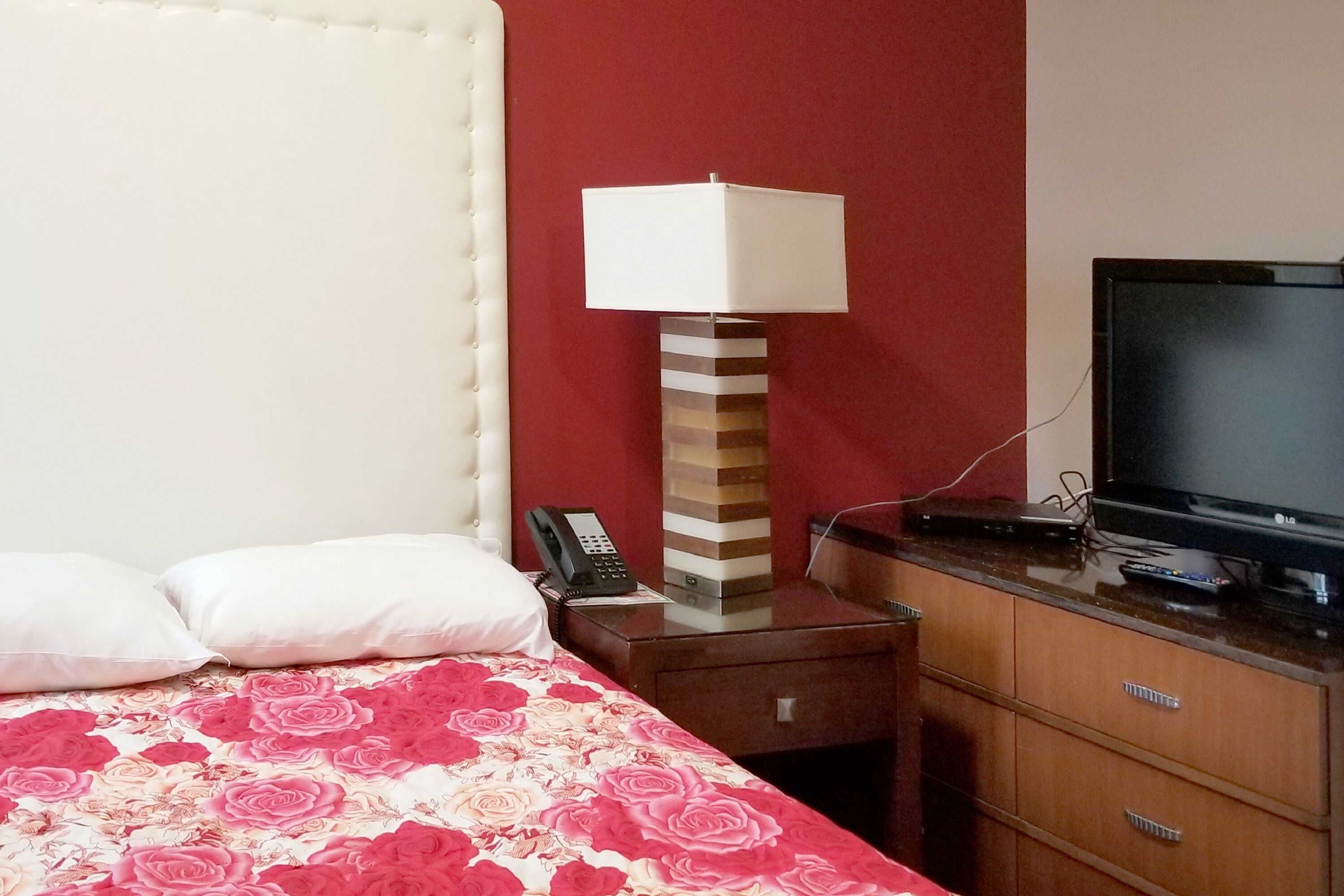 Ein Hotelzimmer mit Bett, Nachttischlampe, Fernseher und Telefon.