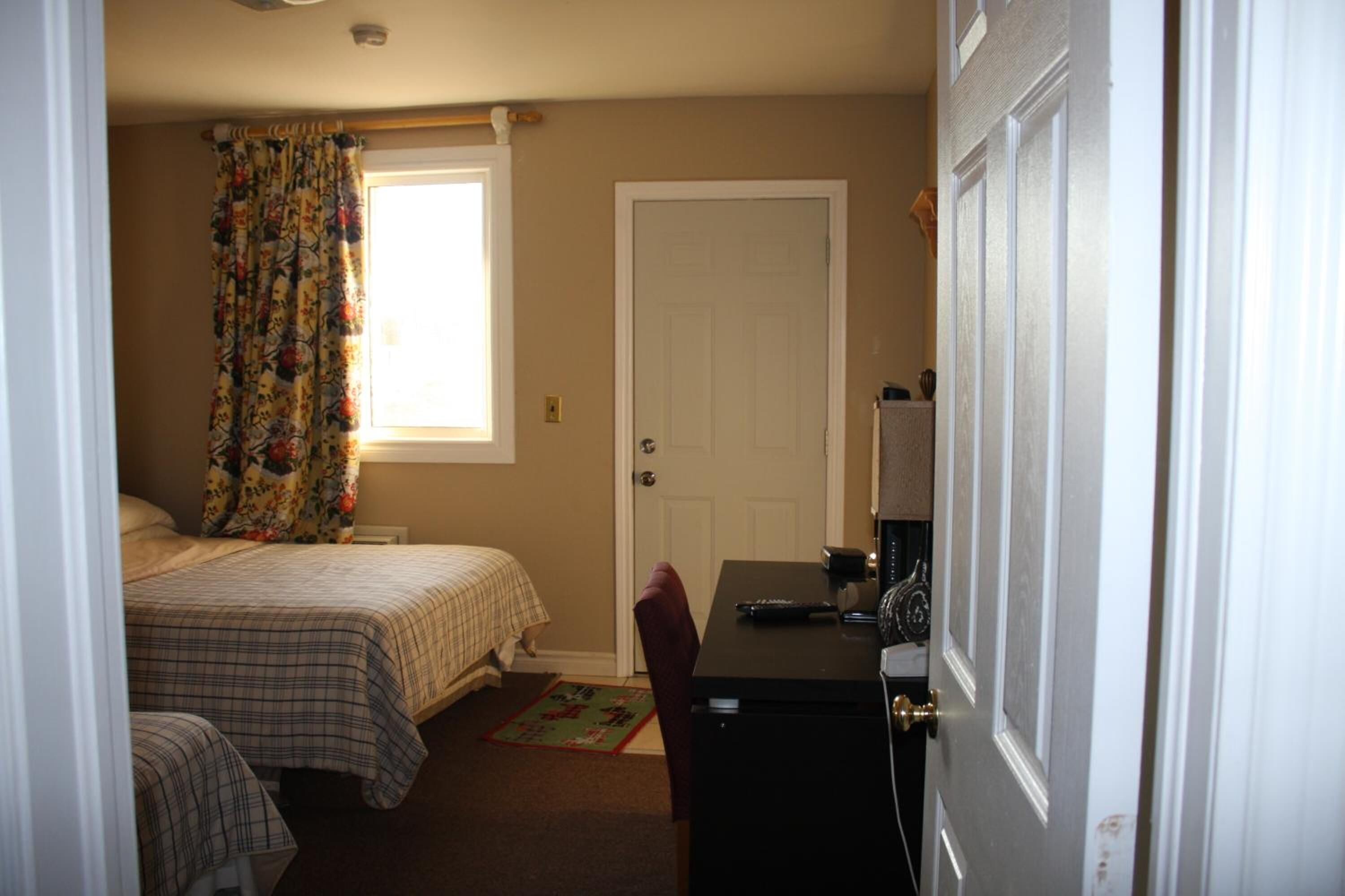 Une chambre avec deux lits, un bureau et une porte.
