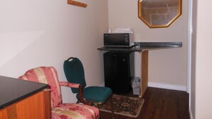 A small kitchenette with a microwave, a chair, and a rug.