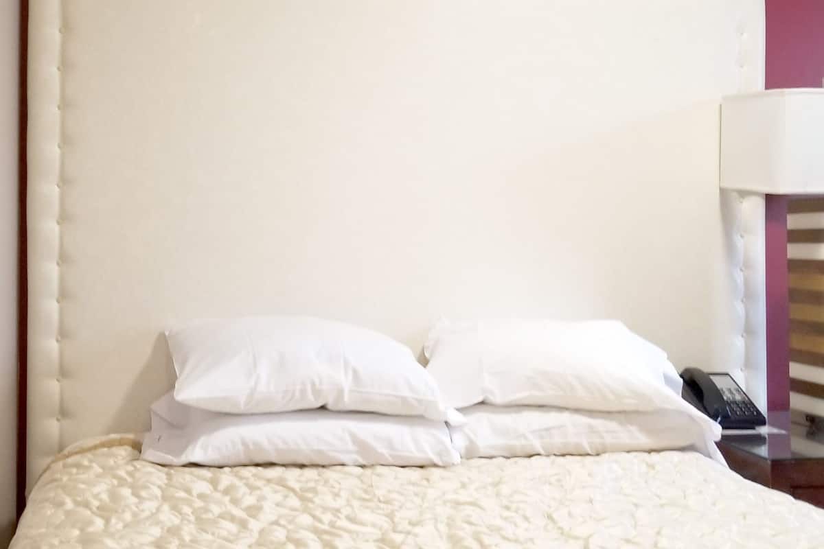 Ein Bett mit weißer Steppdecke und zwei weißen Kissen.