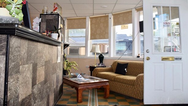 A hotel lobby with a reception desk, a sofa, a coffee table, and a door with a key drop.