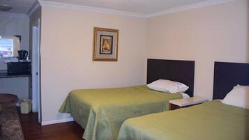Habitación de hotel con dos camas individuales, un escritorio pequeño con silla, microondas y cafetera.