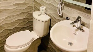 Un baño con pared texturizada, inodoro, bidé y lavamanos.