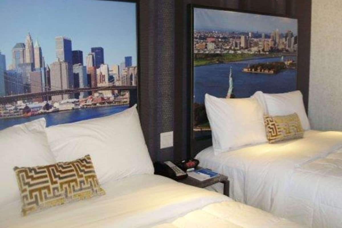 A hotel room with two beds, white bedding, and a cityscape view.