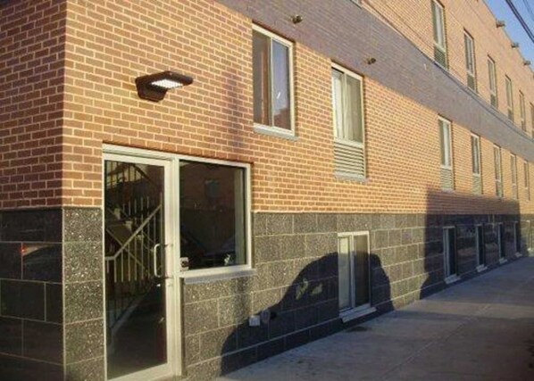 A brick building with a row of windows and a door with a metal gate.