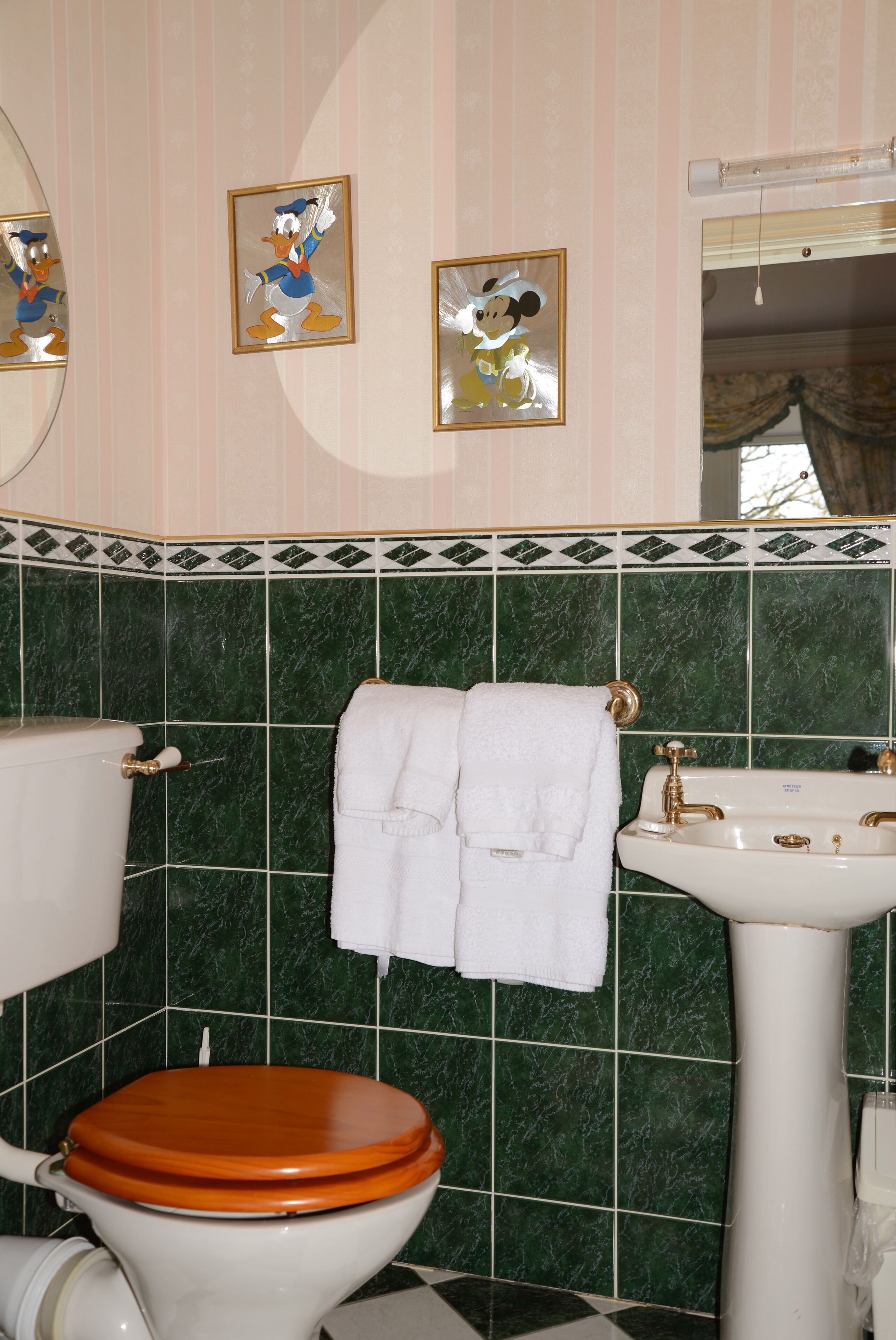 A bathroom with a toilet, sink, and two framed pictures on the wall.