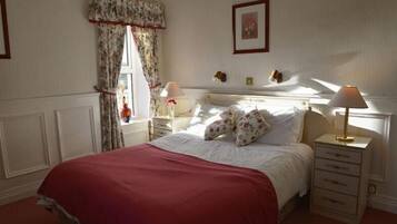 A neatly arranged bedroom with a bed, bedside tables, a lamp, and a framed picture on the wall.