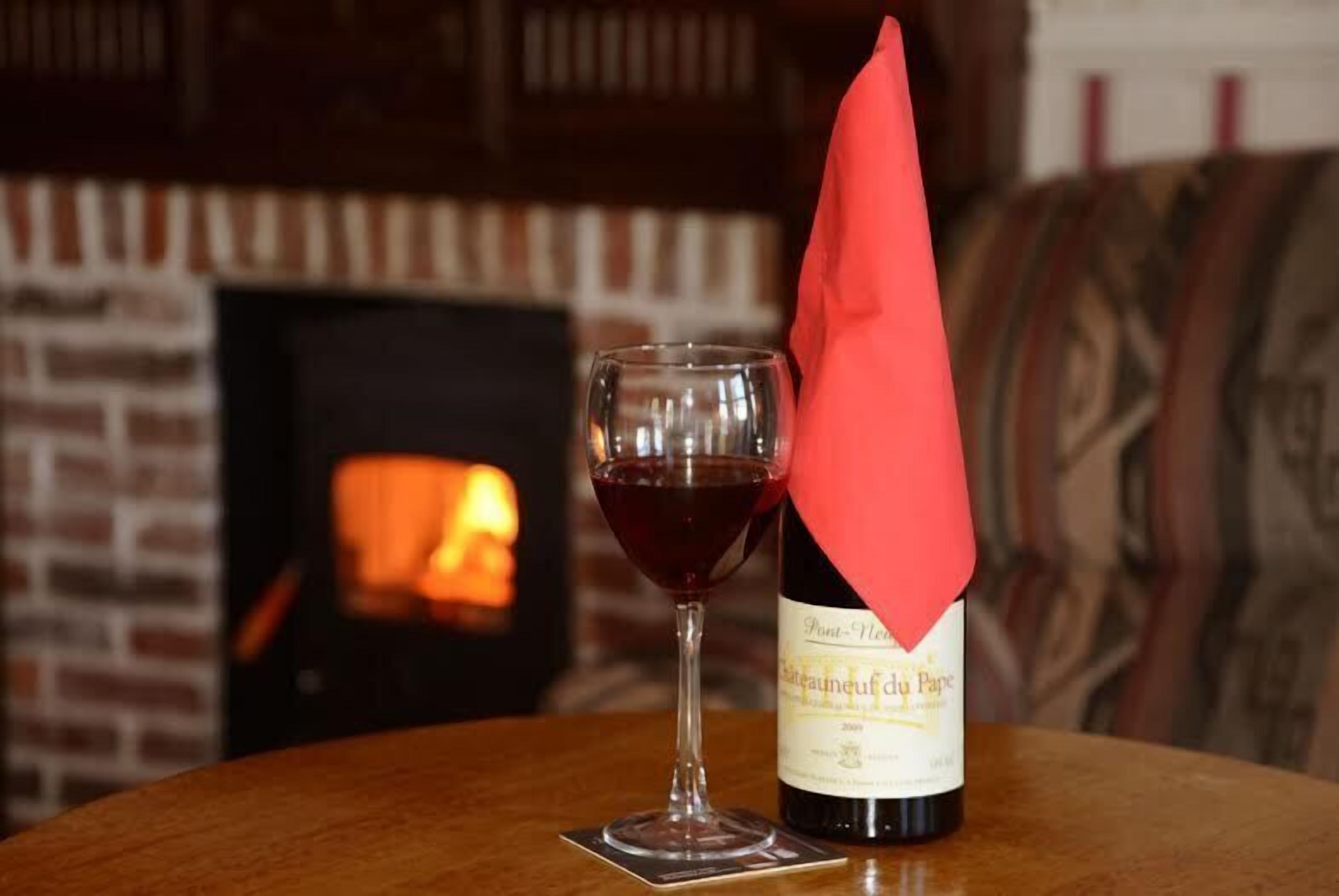 A bottle of wine with a label and a glass of red wine on a table.