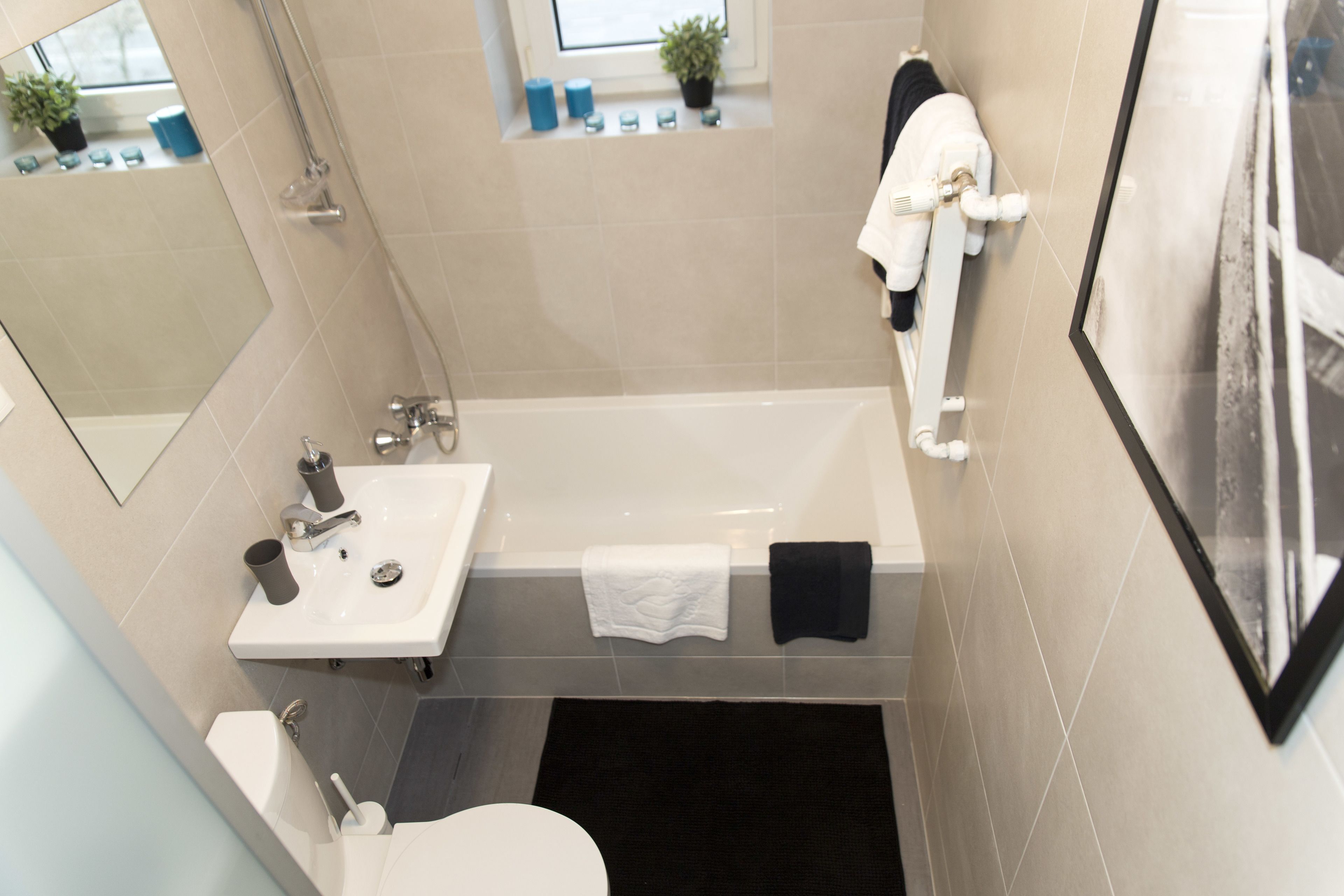 Un baño moderno con bañera, lavamanos e inodoro. Hay toallas y artículos de aseo en la encimera.