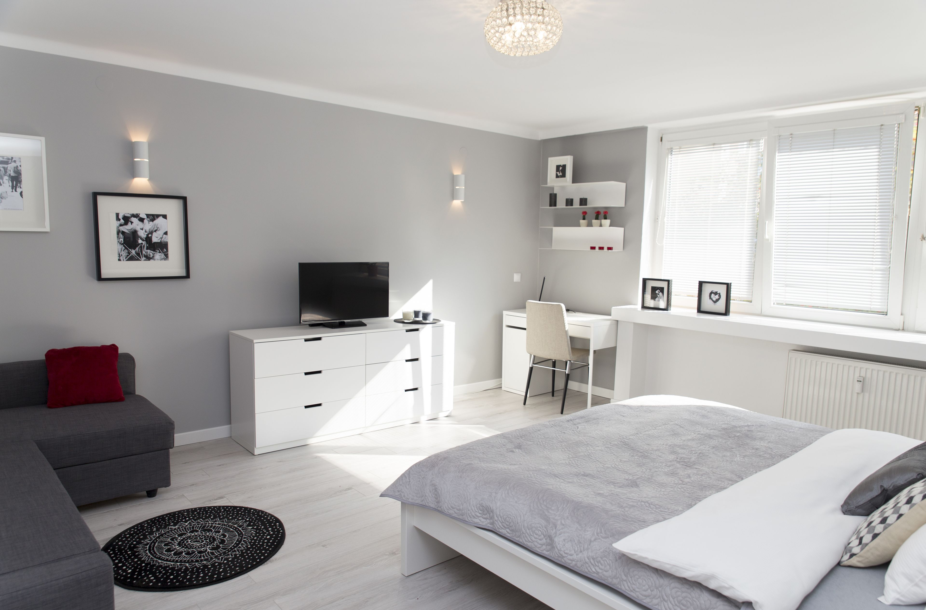 Ein modernes Schlafzimmer mit Bett, Schreibtisch, Fernseher und einer Couch.