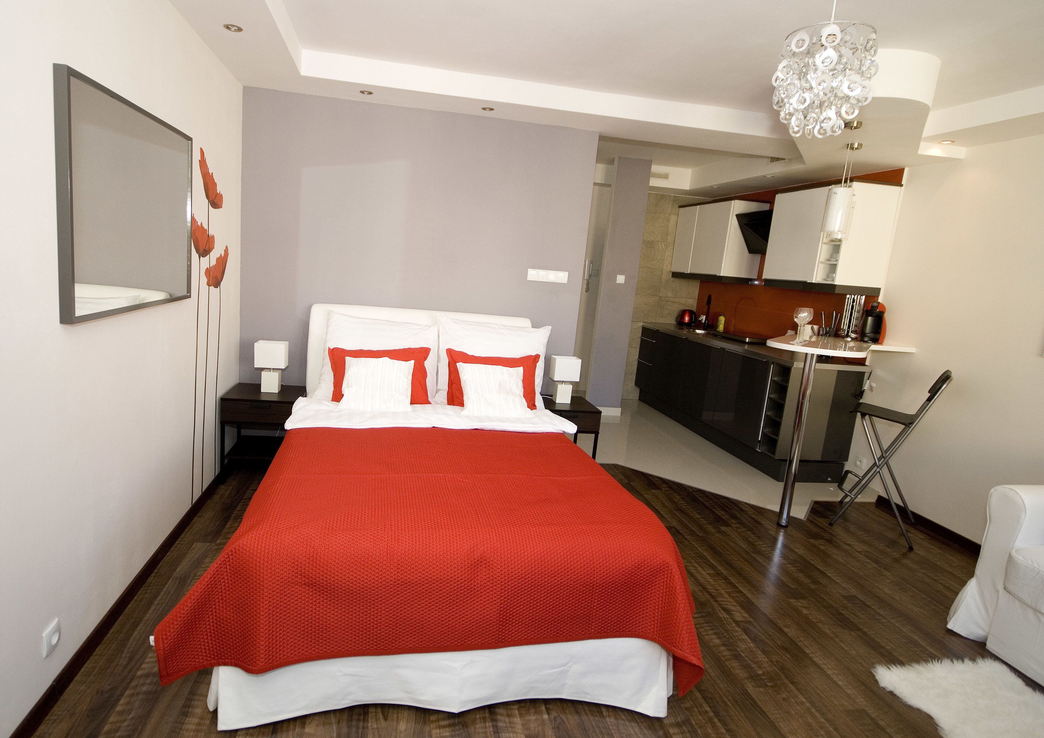A modern hotel room with a large bed, a separate kitchenette, and a small dining area.