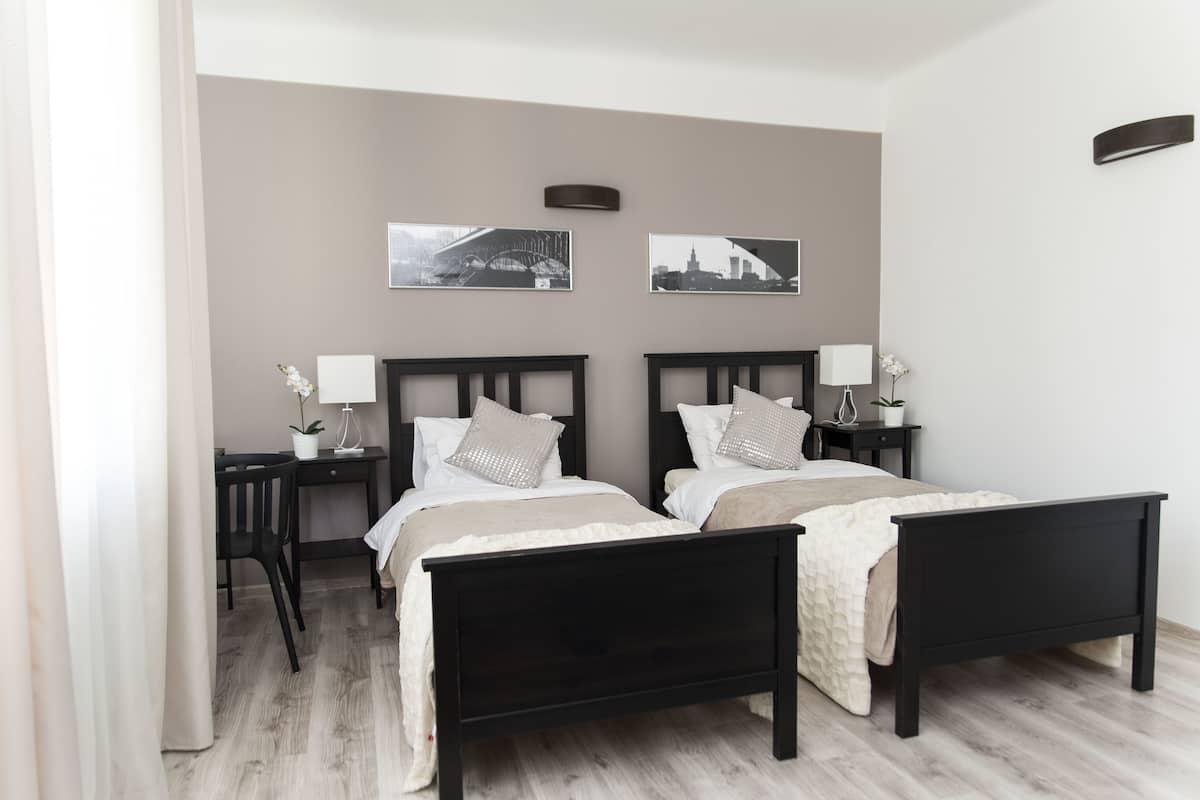 Un lit double avec un cadre en bois, deux tables de chevet et une lampe fixée au mur.