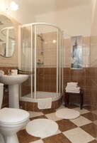 A bathroom with a glass-enclosed shower, a sink, a toilet, and a mirror.