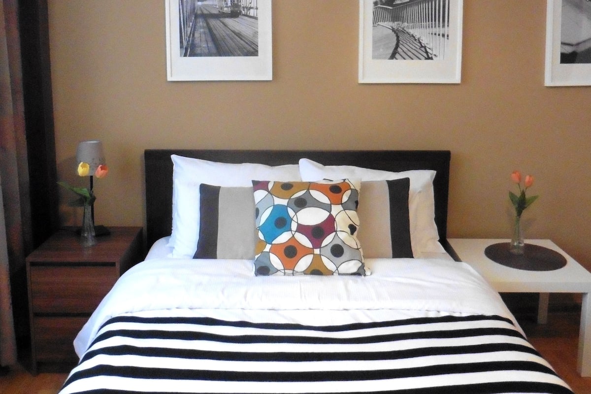 Une chambre d’hôtel avec un lit, une table de chevet et deux tableaux encadrés accrochés au mur.