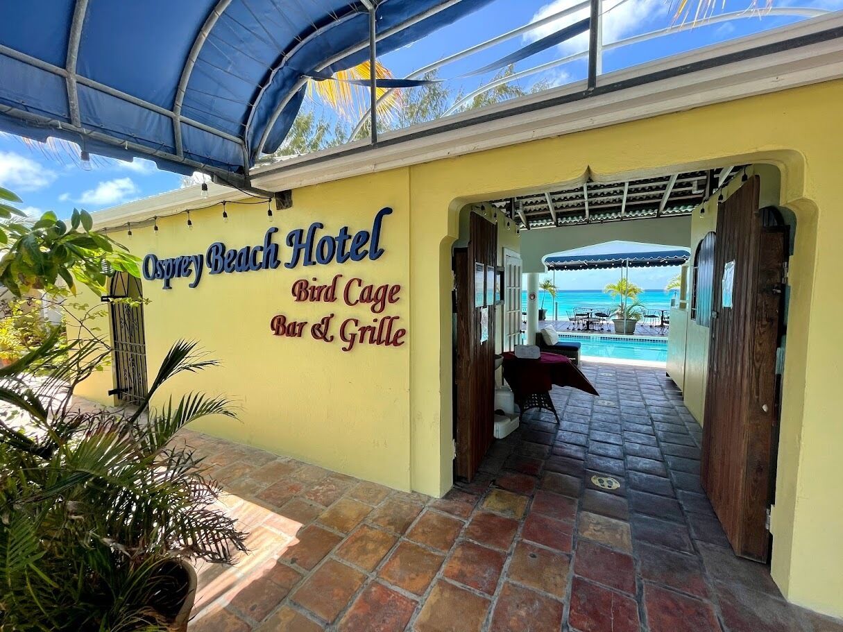 L’entrée de l’hôtel Osprey Beach, avec une enseigne indiquant le « Bird Cage Bar & Grille ».