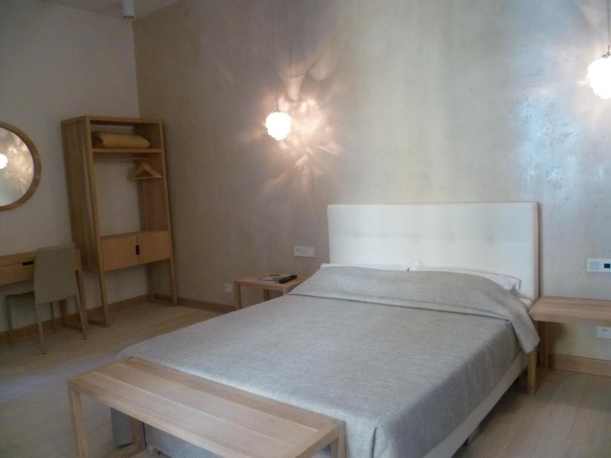 Un dormitorio con cama, mesita de noche, armario de madera, escritorio y silla.