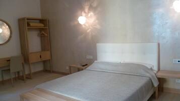 Un dormitorio con cama, mesita de noche, armario de madera, escritorio y silla.