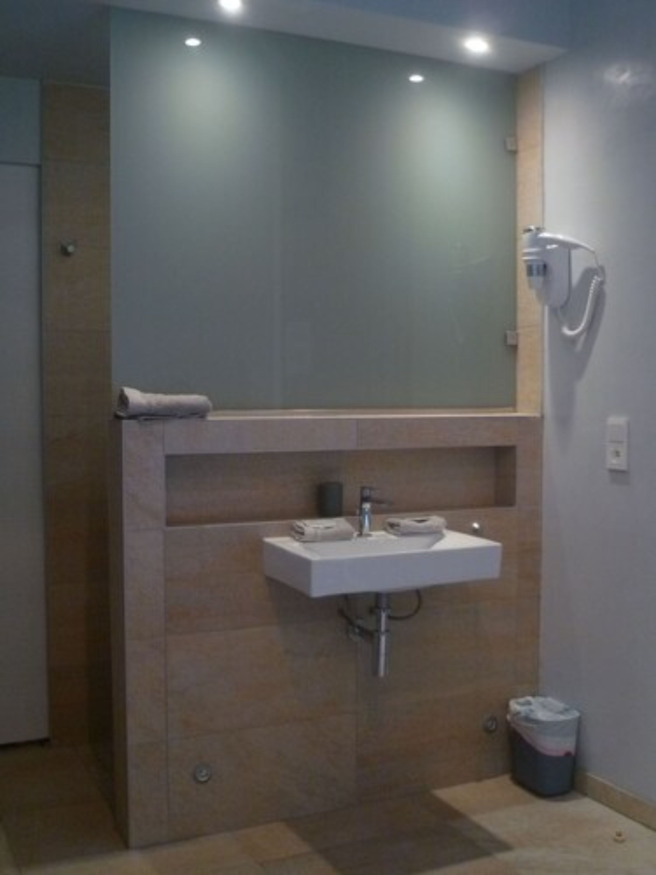 A bathroom with a sink, mirror, towel rack, and shower.