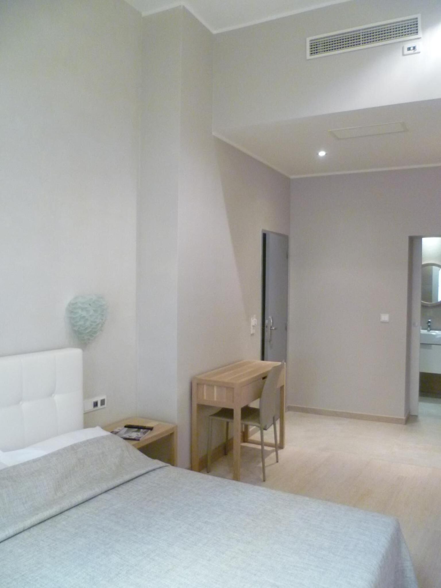 Un dormitorio con una cama, un escritorio y una silla. Hay una puerta que da al baño.