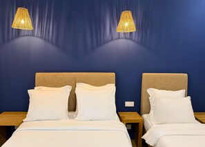 A hotel room with two beds, a blue wall, and two hanging lamps. - Hotel De La Mer (Nice)