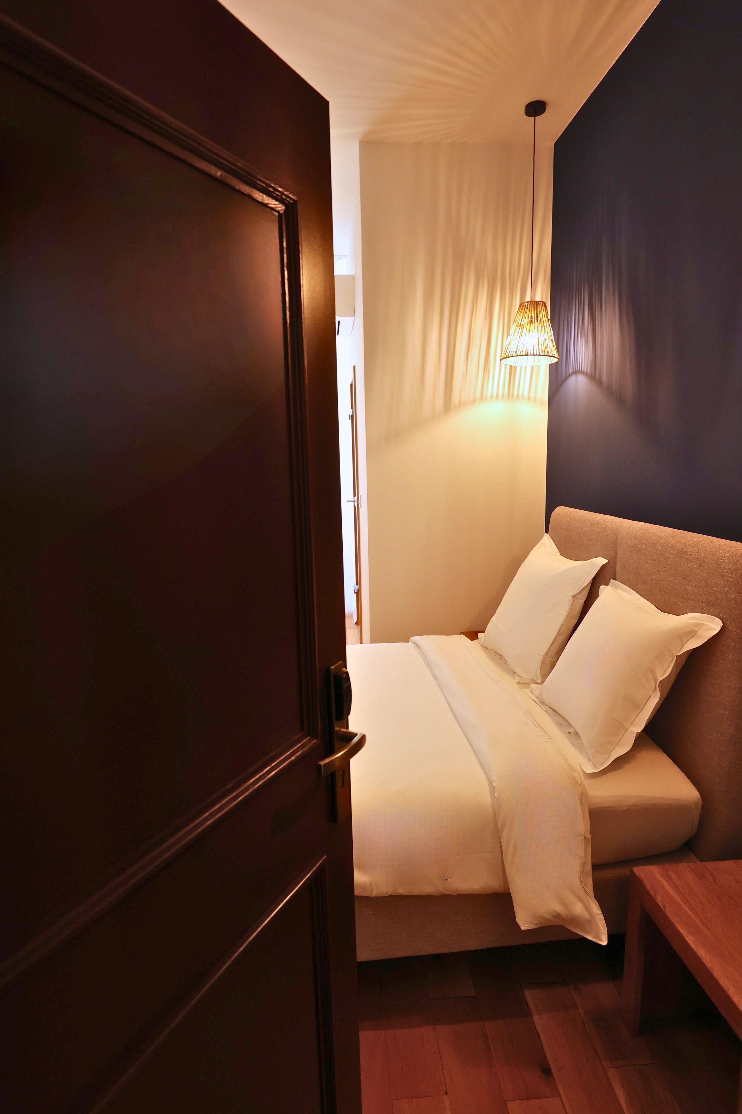 A bedroom with a bed, bedside table, and a hanging light fixture.