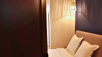 A bedroom with a bed, bedside table, and a hanging light fixture.