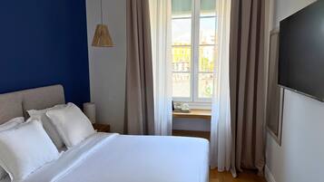 Een hotelkamer met een bed, gordijnen, een raam en een televisie.