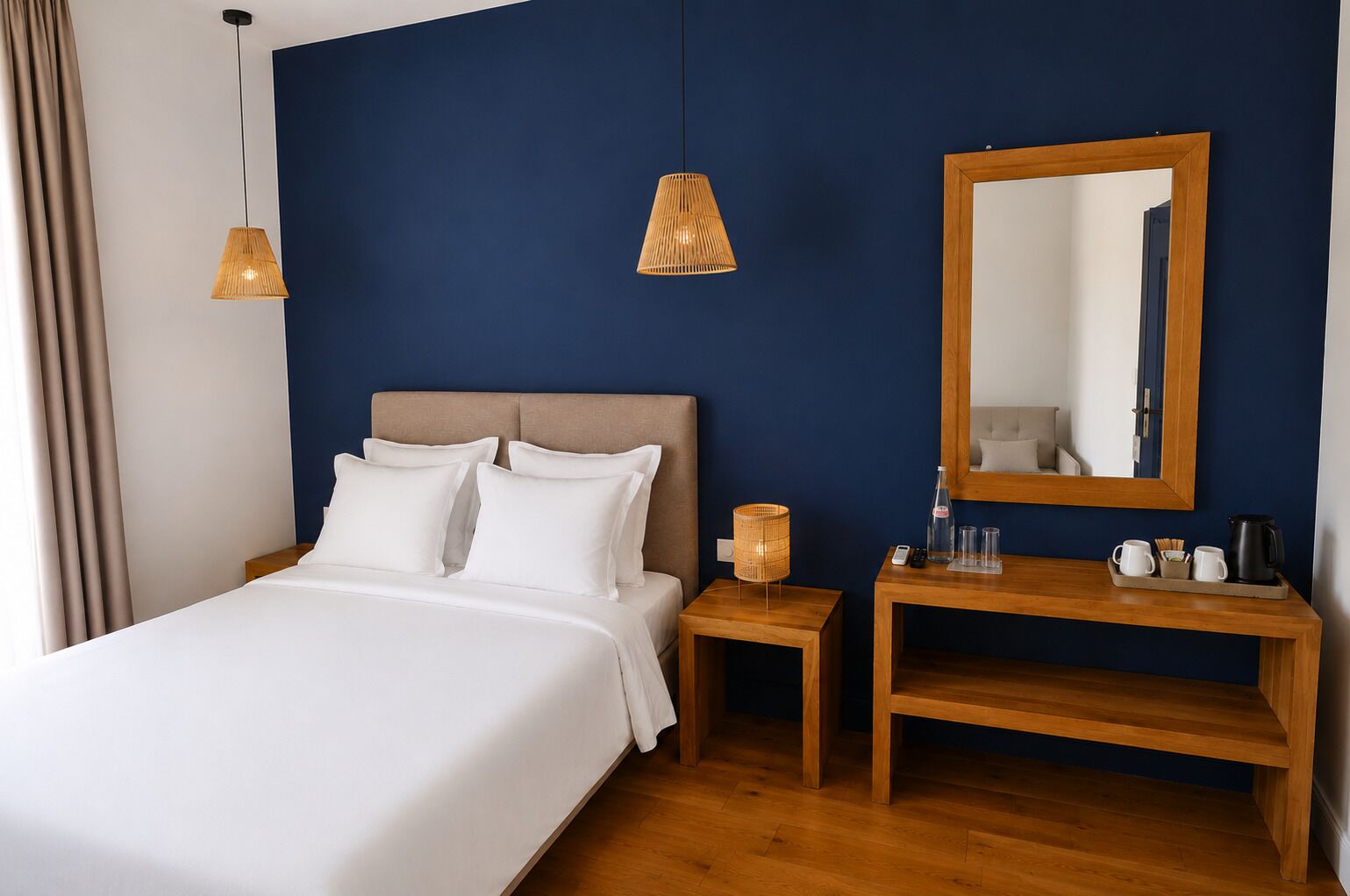 Une chambre d’hôtel comprenant un lit, une table de chevet, une lampe, un miroir et une petite table en bois.