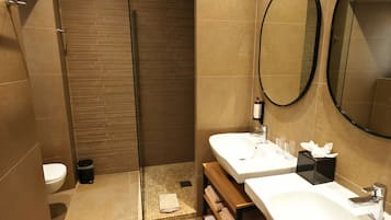 A modern bathroom with a shower, toilet, and two sinks with mirrors.