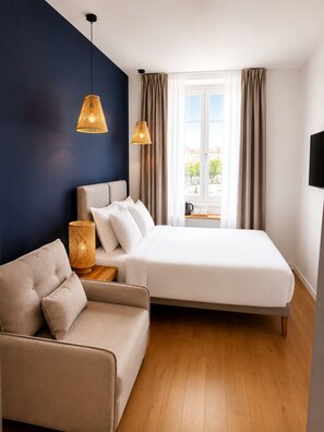 Habitación de hotel moderna con cama, sofá y dos lámparas colgantes.