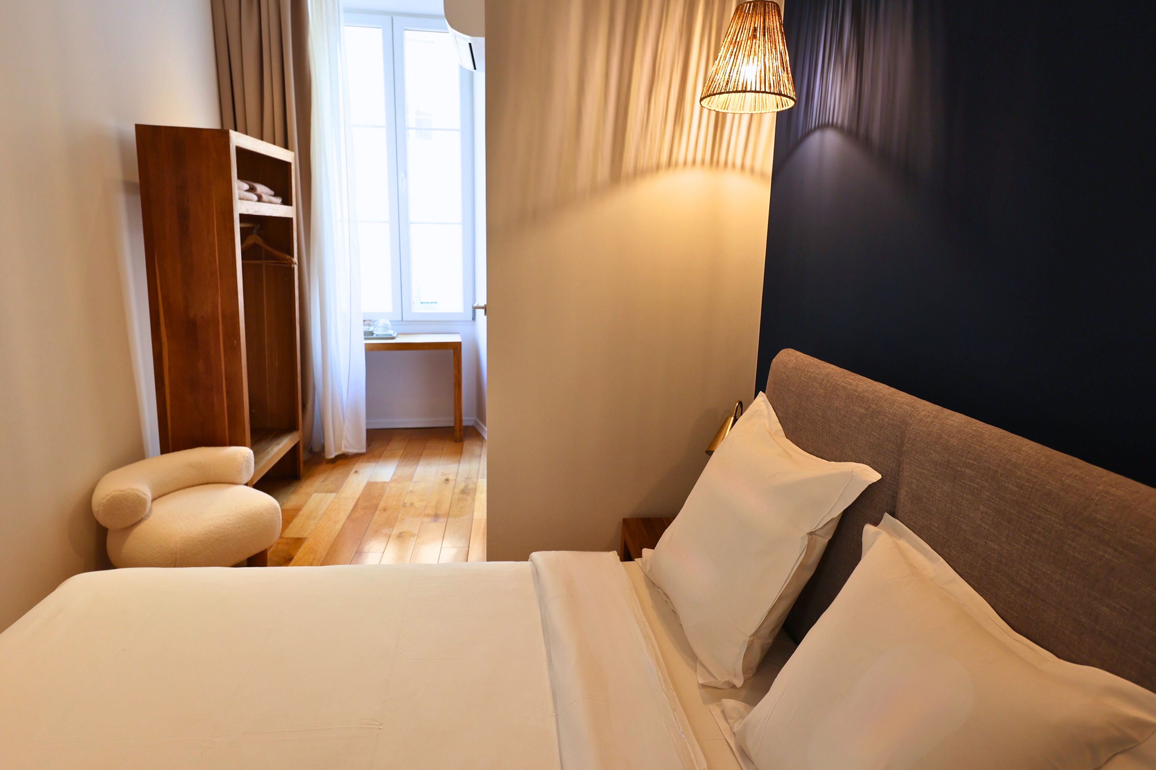 Un dormitorio con cama, mesita de noche, lámpara, armario y vistas al exterior.