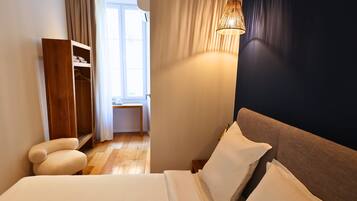 Un dormitorio con cama, mesita de noche, lámpara, armario y vistas al exterior.