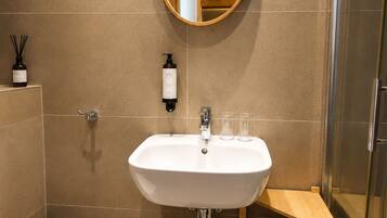 Une salle de bain avec un lavabo blanc, un miroir, des toilettes et un espace douche.