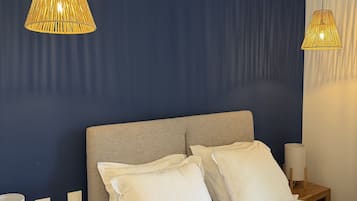 A bedroom with a bed, two bedside tables, and two hanging lamps.