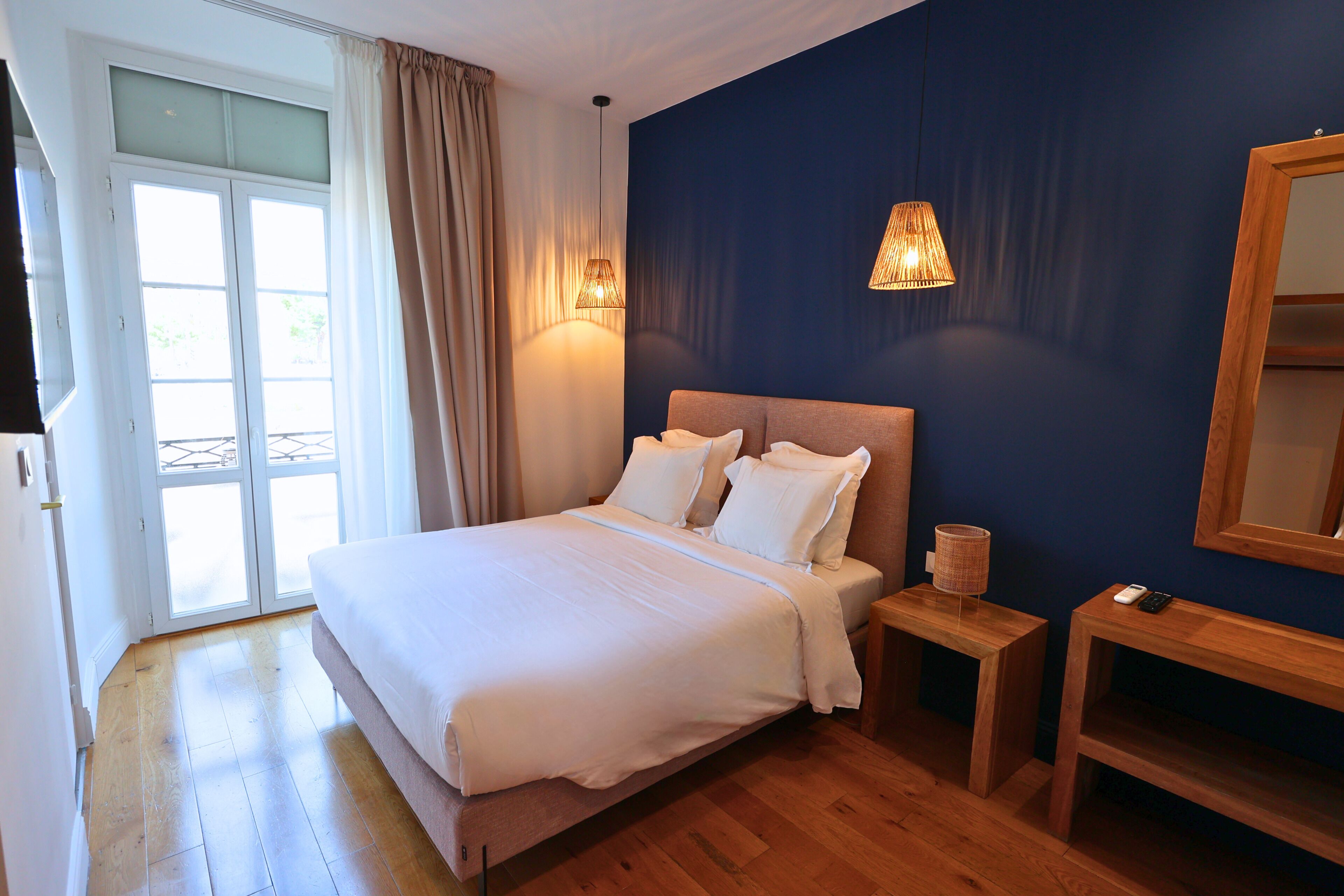A bedroom with a bed, bedside tables, a lamp, and a mirror.